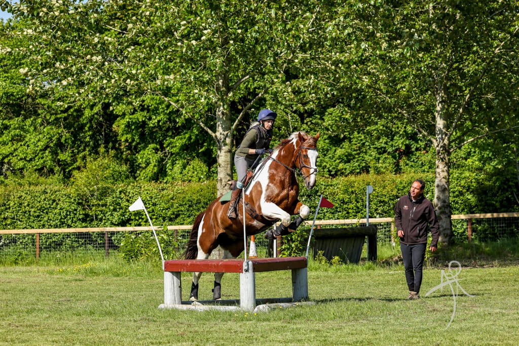 Horse and rider tacking a corner cross country fence with Roland coaching